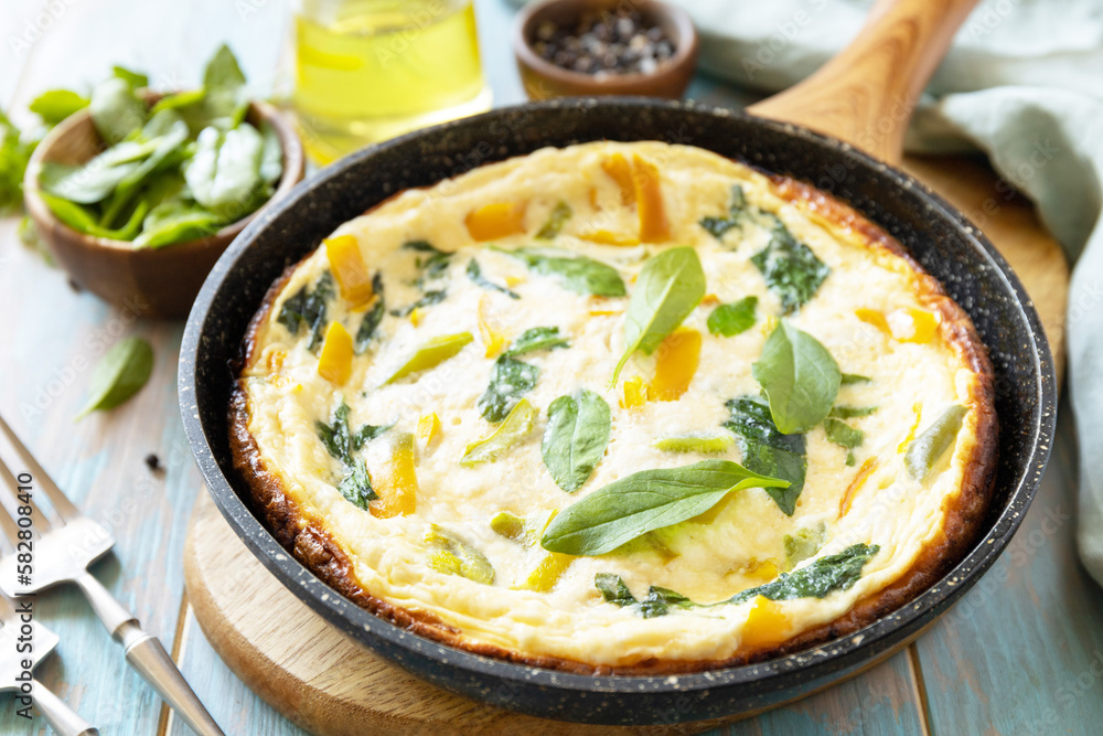 Healthy frittata or stuffed omelette in pan on rustic wooden background. Italian omelette with organic spinach and bell pepper. Healthy frittata or stuffed omelette in pan on rustic wooden background. Italian omelette with organic spinach and bell pepper.