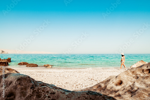Panorama attractive caucasian tourist woman in white bikini walk on white sand beach alone explore middle east.Persian gulf Mirella island. Musandam.Oman