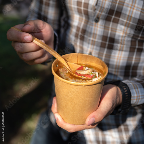 Takeaway food, soup in takeaway paper cup close-up in hands