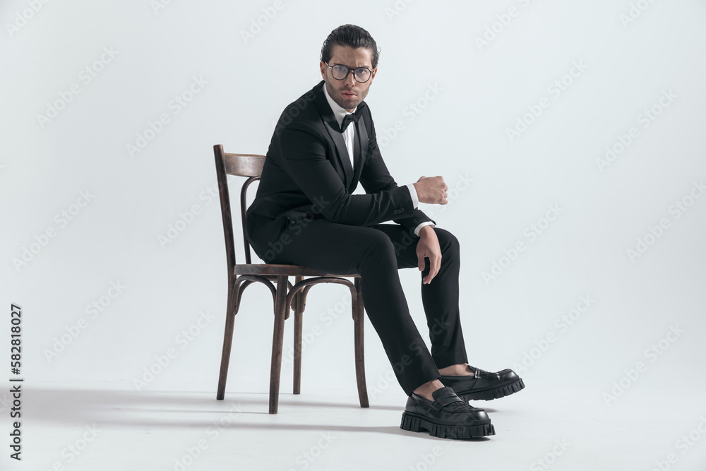 cool elegant groom with glasses posing while sitting with elbows on thighs cool elegant groom with glasses posing while sitting with elbows on thighs