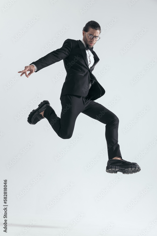 dynamic elegant man in black tuxedo jumping in the air