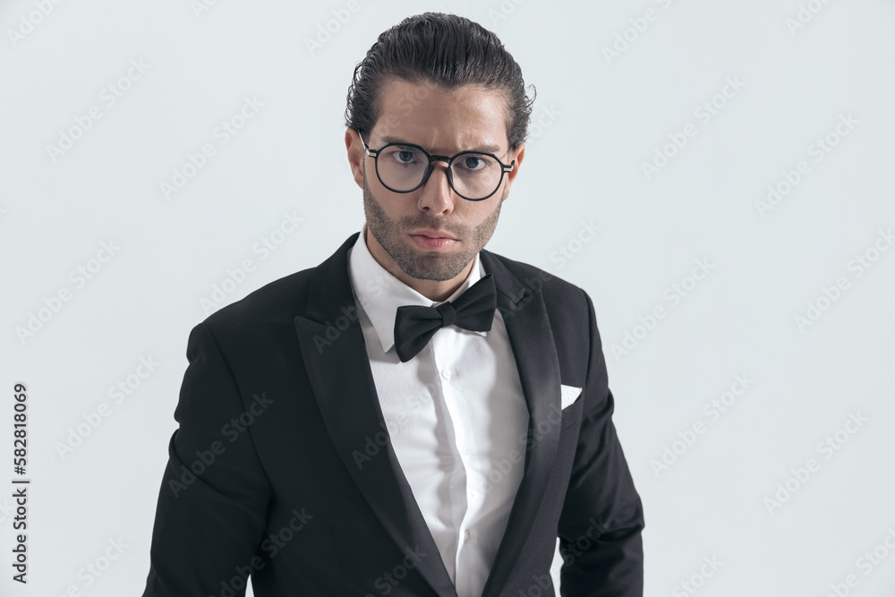 young elegant man with glasses in black tuxedo frowning and posing young elegant man with glasses in black tuxedo frowning and posing