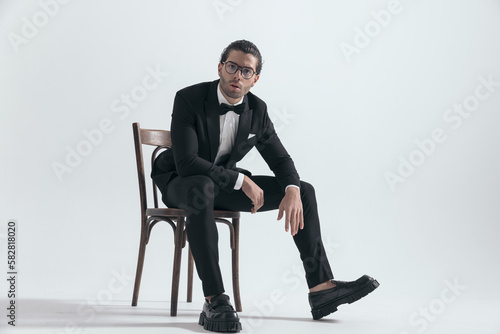 cool fashion man with glasses sitting with elbows on knees