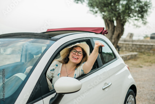 Car driver woman smiling showing new car keys and car. Female driving rented cabrio on summer vacation © satura_