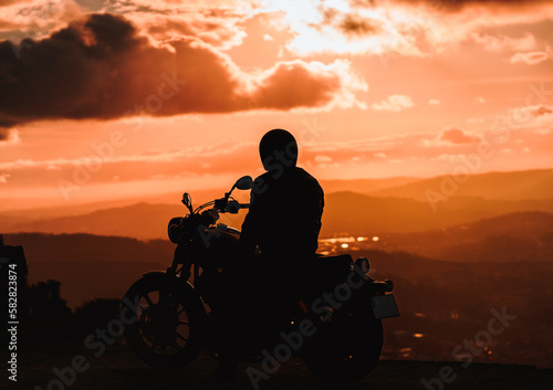 Motorcyclist wacthing the sunset behind the mountains 