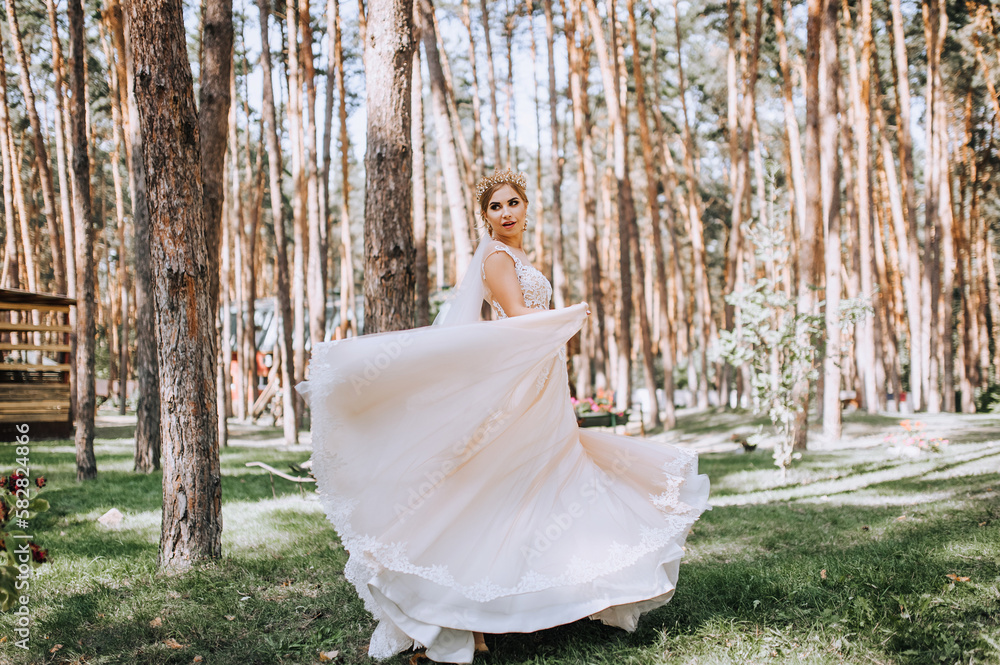 Φωτογραφία A beautiful young stylish blonde bride in a white long lace dress is dancing, spinning in the forest, in the park