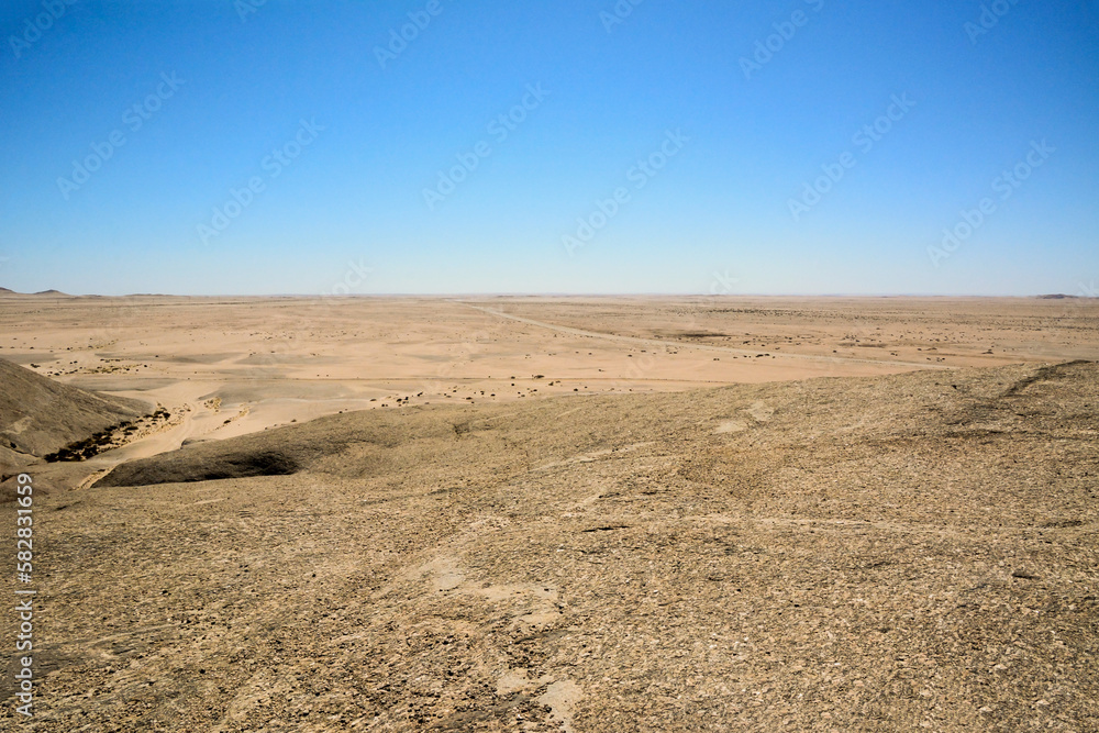 Arid desert hills with rocks all the way to the horizon against a blue sky background