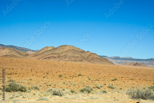 A rocky hill on a mountain slope near the desert against a clear blue sky. World climate change and global warming