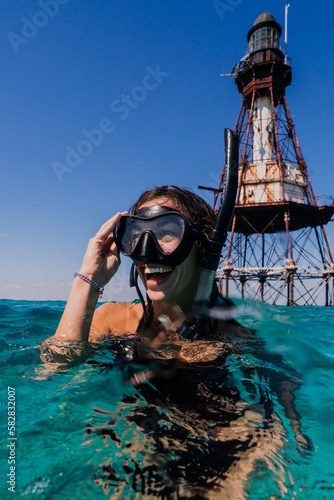 Cheerful, joyful, young athletic woman, snorkeling and swimming on beach vacation, having fun in the tropical water, with a big toothy smile, laughing, enjoying her honeymoon	