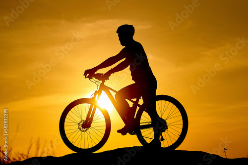 Fototapeta Naklejka Na Ścianę i Meble -  Sunset shadow of cyclist. Silhouette biking summer ride.