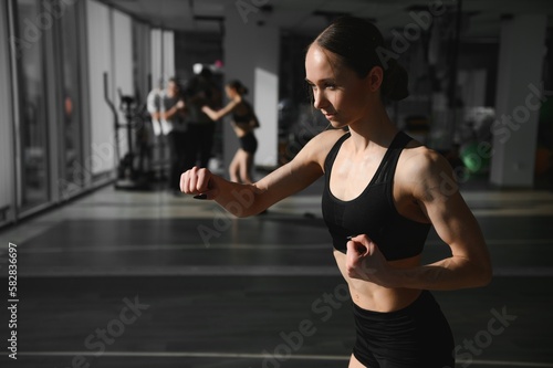Boxing woman during exercise-gray background at gym