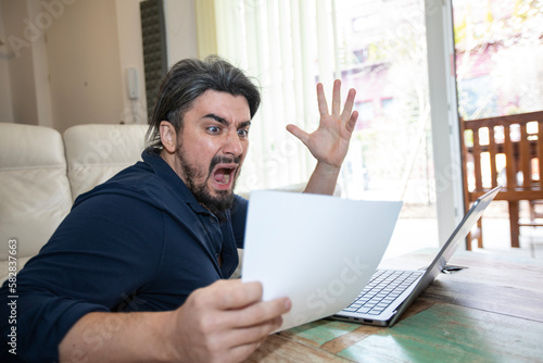 Handsome young man shocked over high bill in office photo