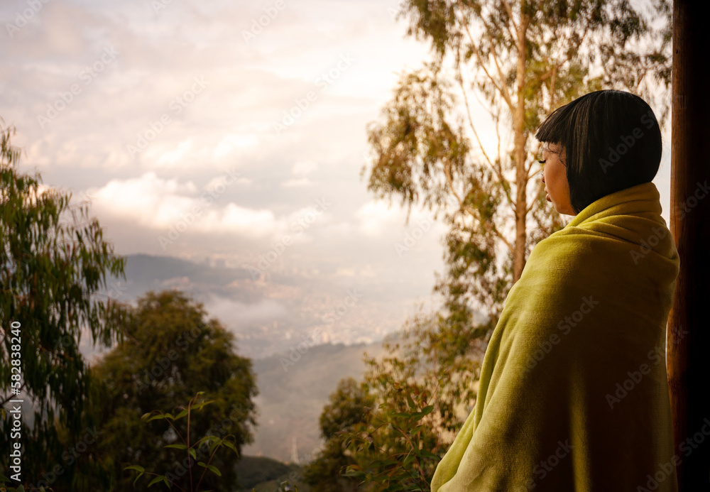 Beautiful woman in blanket standing on terrace in sunrise enjoying the moment, rural travel concept Beautiful woman in blanket standing on terrace in sunrise enjoying the moment, rural travel concept