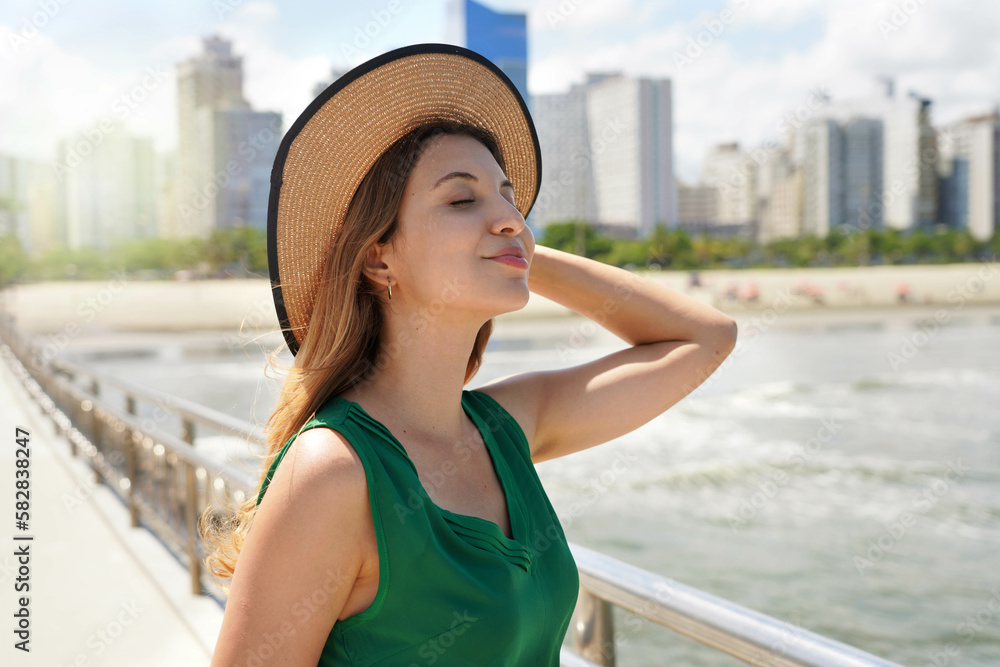 Fashion girl breathing relaxed enjoying wind on her face with skyscrapers and beach