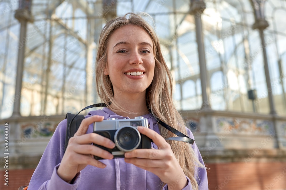 Young caucasian woman captures artistic beauty of the crystal palace in Madrid with her camera.
