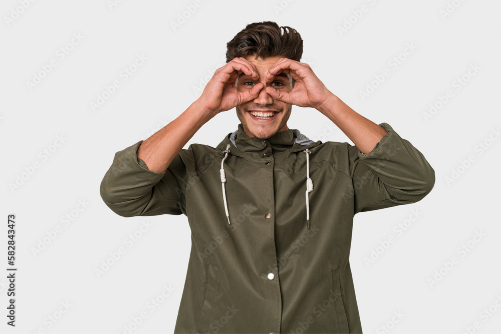 Young handsome caucasian man isolated on white background showing okay sign over eyes Young handsome caucasian man isolated on white background showing okay sign over eyes