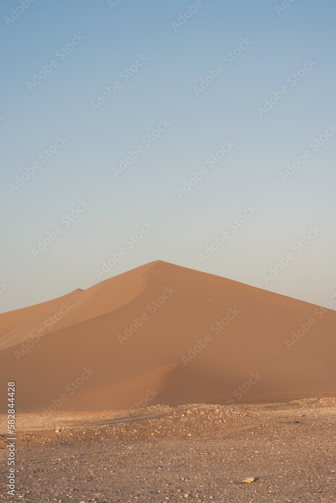 Golden yellow sand dune in contrast with soft blue sky in the dry hot desert