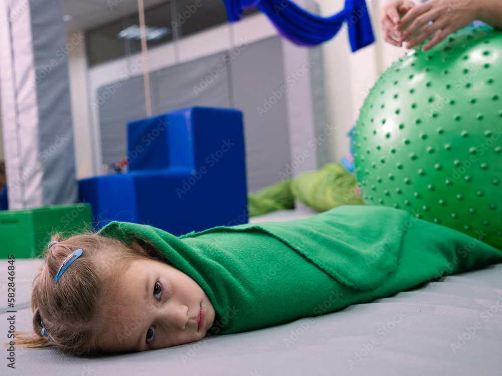 Physical therapist working with little girl in sensory room. Exercising