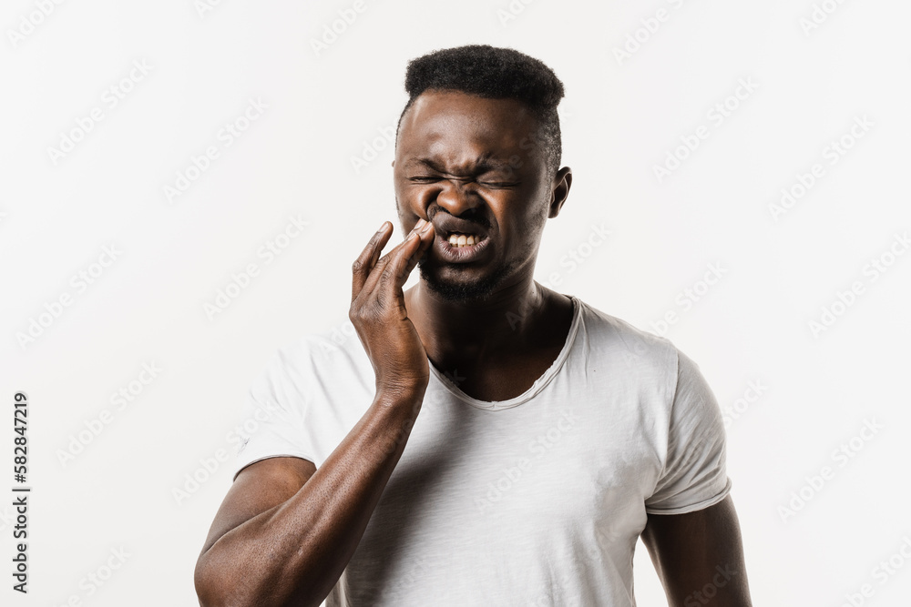 Toothache of african man on white background. African american is touching cheek and feeling teeth hurt on white background. Tooth decay, infection or injury to the tooth or gums. Toothache of african man on white background. African american is touching cheek and feeling teeth hurt on white background. Tooth decay, infection or injury to the tooth or gums.
