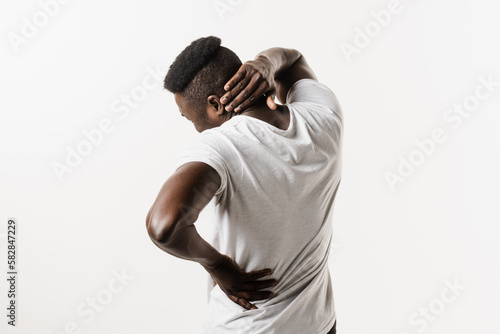 African man feel spine and neck pain because of spinal nerves compression on white background. Cervical spine osteochondrosis is radicular syndromes of african american man.