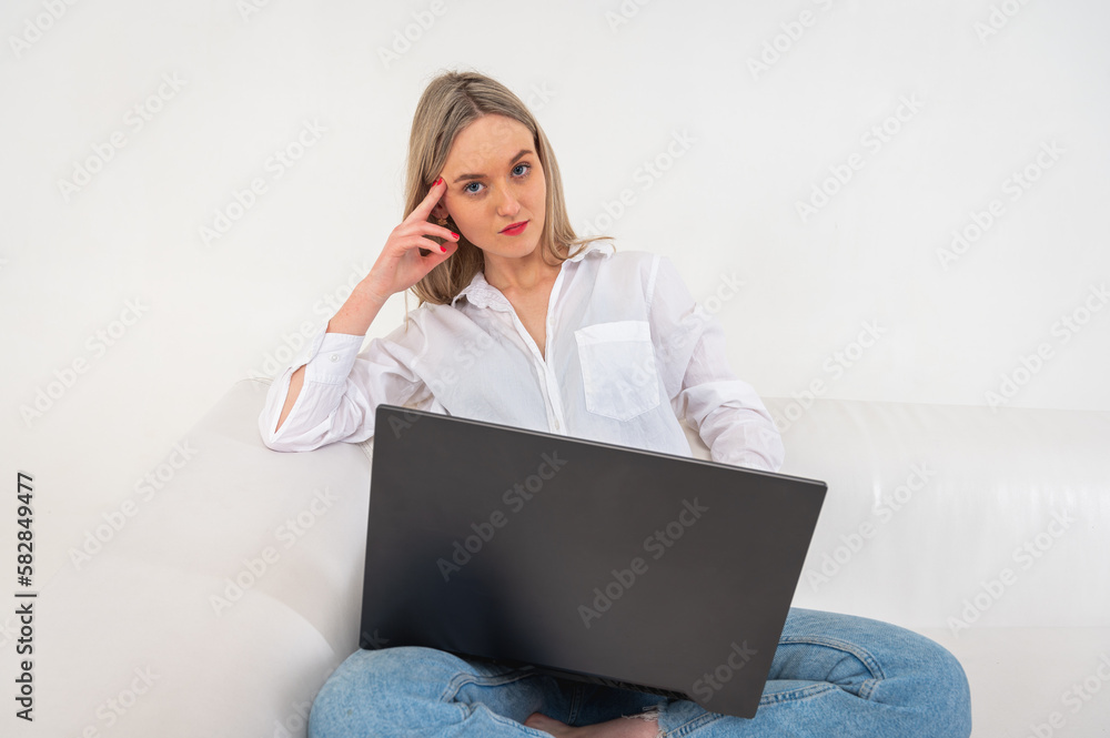 young pretty girl sitting on laptop sitting on sofa isolated on light background girl shopping or chatting online on social networks having fun watching movie. Place for writing young pretty girl sitting on laptop sitting on sofa isolated on light background girl shopping or chatting online on social networks having fun watching movie. Place for writing