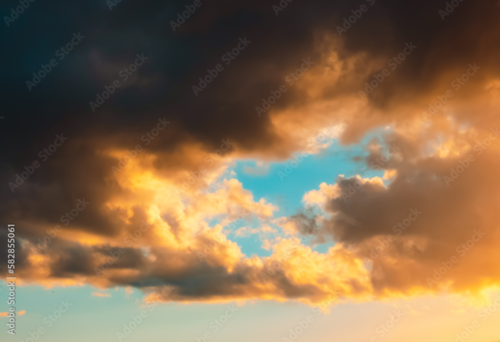 Dramatic sky. Dark cumulus clouds in sunlight on a light blue background. After storm. Sunny evening. It cleared up. Before a thunderstorm, hurricane or storm. Air element. Wallpaper. Moving ciclone