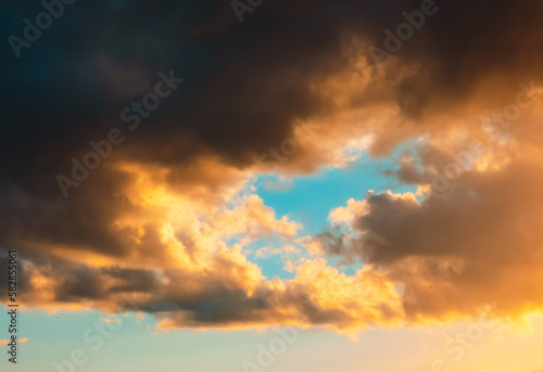 Dramatic sky. Dark cumulus clouds in sunlight on a light blue background. After storm. Sunny evening. It cleared up. Before a thunderstorm  hurricane or storm. Air element. Wallpaper. Moving ciclone