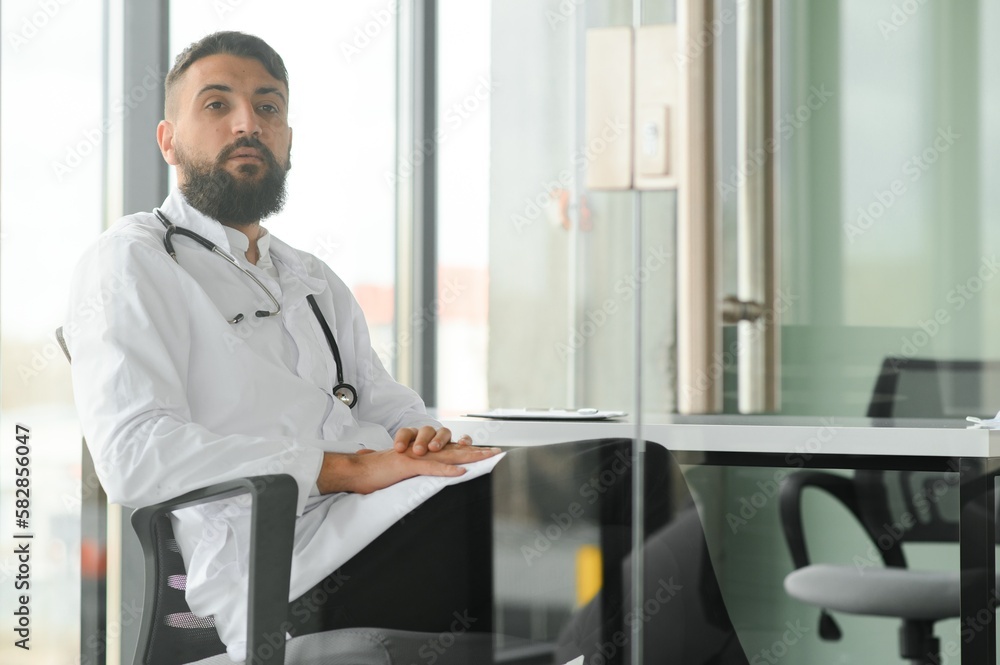 Fototapeta premium Portrait of pleasant young Arabian doctor in white coat.