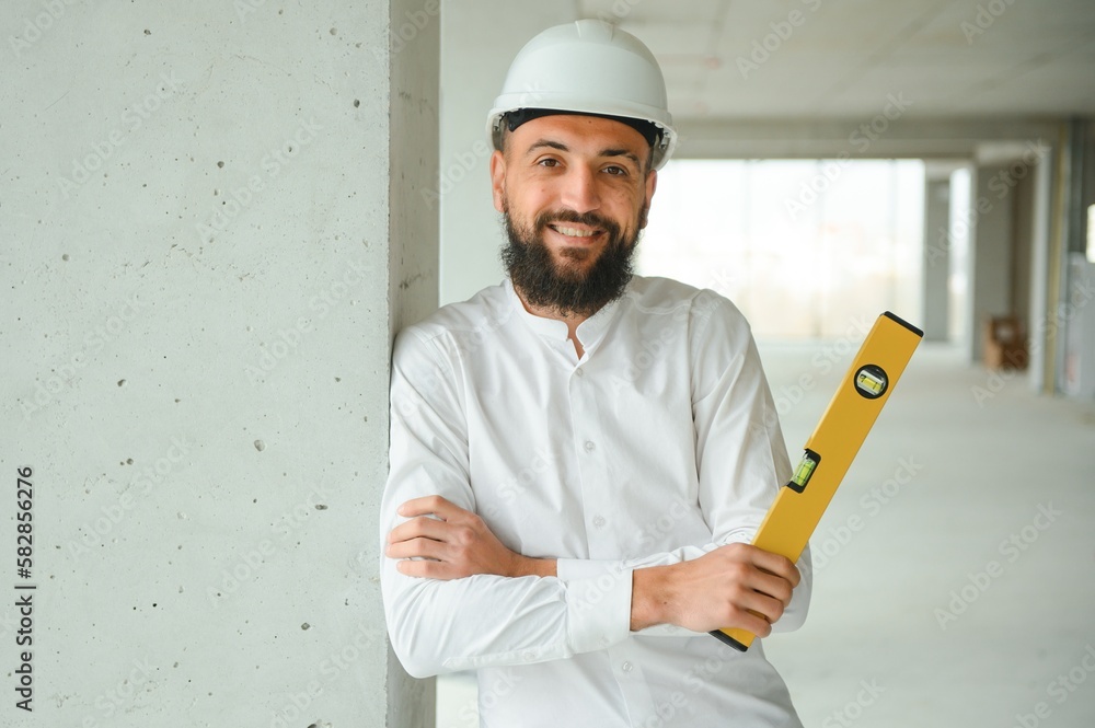 Serious busy young attractive arabic industrial engineer in hard hat with project drawings in factory interior. Professional and industry, builder architect job, worker checking work at plant indoor Serious busy young attractive arabic industrial engineer in hard hat with project drawings in factory interior. Professional and industry, builder architect job, worker checking work at plant indoor