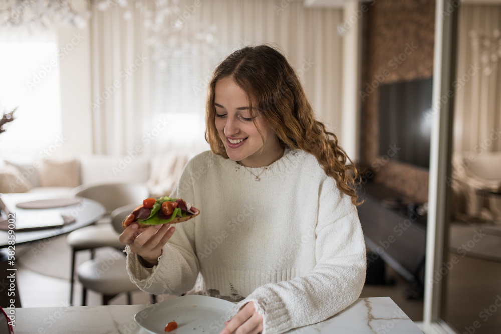 Young girl having her breakfast sandwich at home. Young girl having her breakfast sandwich at home.