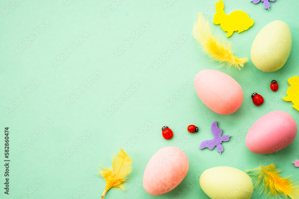 Easter background. Eggs, rabbit, spring flowers and butterfly. Flat lay mock up at green background.