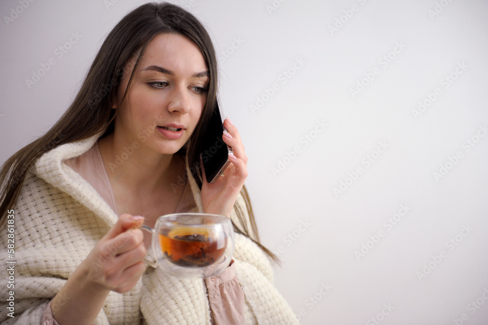 sick elegant 20 years old housewife in roll neck sweater and cardigan drinking cup of hot tea with ginger, lemon and honey against winter light blue background. High quality photo sick elegant 20 years old housewife in roll neck sweater and cardigan drinking cup of hot tea with ginger, lemon and honey against winter light blue background. High quality photo