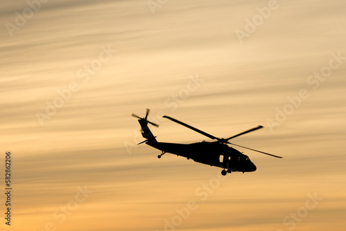 Black hawk helicopter silhouette with cloud streaks