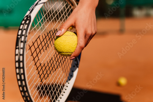 Caucasian european woman hold yellow green ball, playing tennis match on clay court surface on weekend free time sunny day. Female player ready to serve. Professional sport concept  © Volodymyr