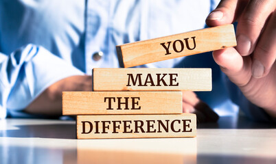 Close up on businessman holding a wooden block with "You Make The Difference" message
