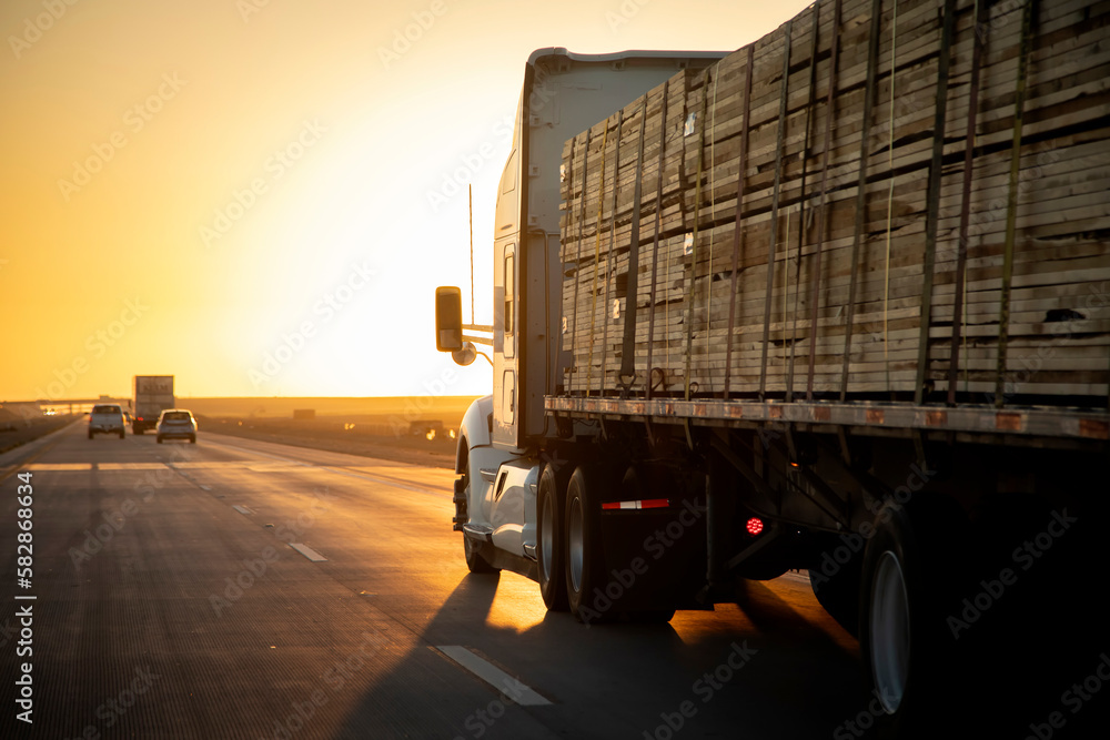Φωτογραφία Long Haul 18 Wheel Truck driving on a highway with a load of lumber at sunrise o