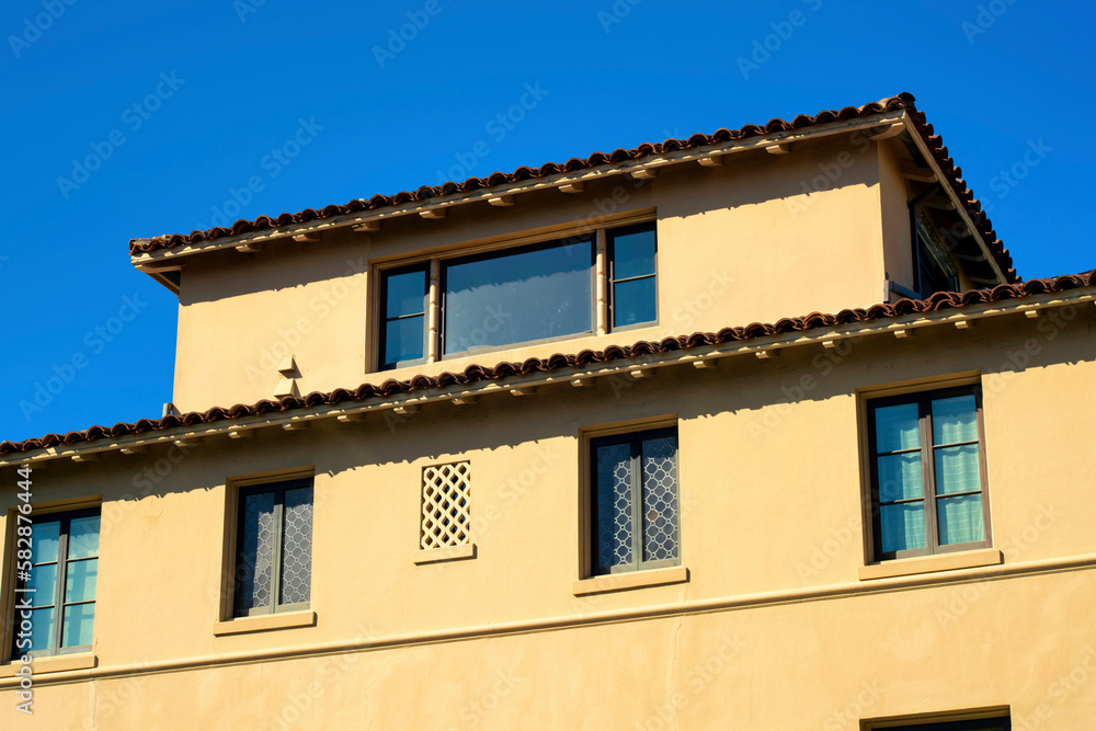 Beige or creame colored stucco cement building with gray roof tiles and exterior facade in downtown city with windows