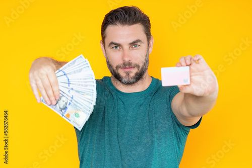 Handsome man holding money isolated over grey studio. Money in dollar banknotes. Pile of cash, finance, investment and money saving.