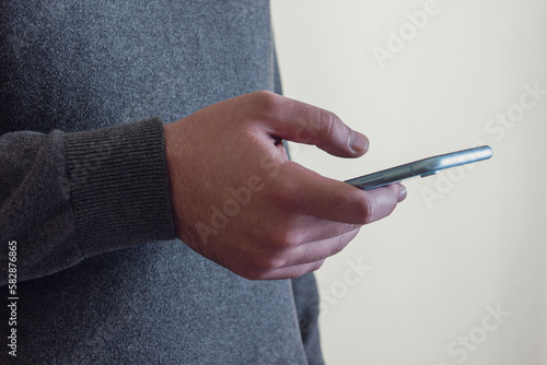A man in a gray turtleneck holds a phone in his hand