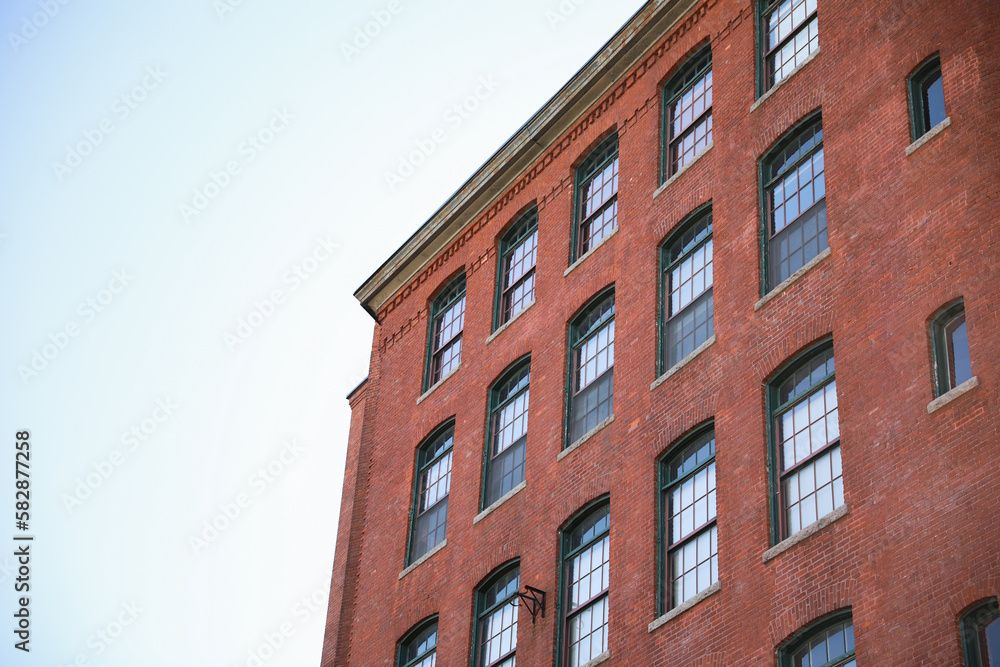 historic brick building structure with glass windows of urban apartment building old residential construction in boston downtown street with blue sky and business concept symbolizing monotonous work