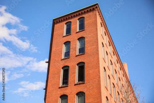 historic brick building structure with glass windows of urban apartment building old residential construction in boston downtown street with blue sky and business concept symbolizing monotonous work