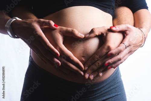 Pregnant woman with her hands and her husband's hands on her belly (ID: 582886895)