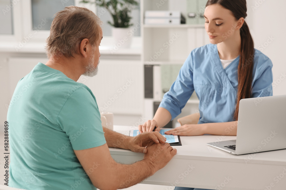 Obraz premium Professional orthopedist consulting patient at table in clinic