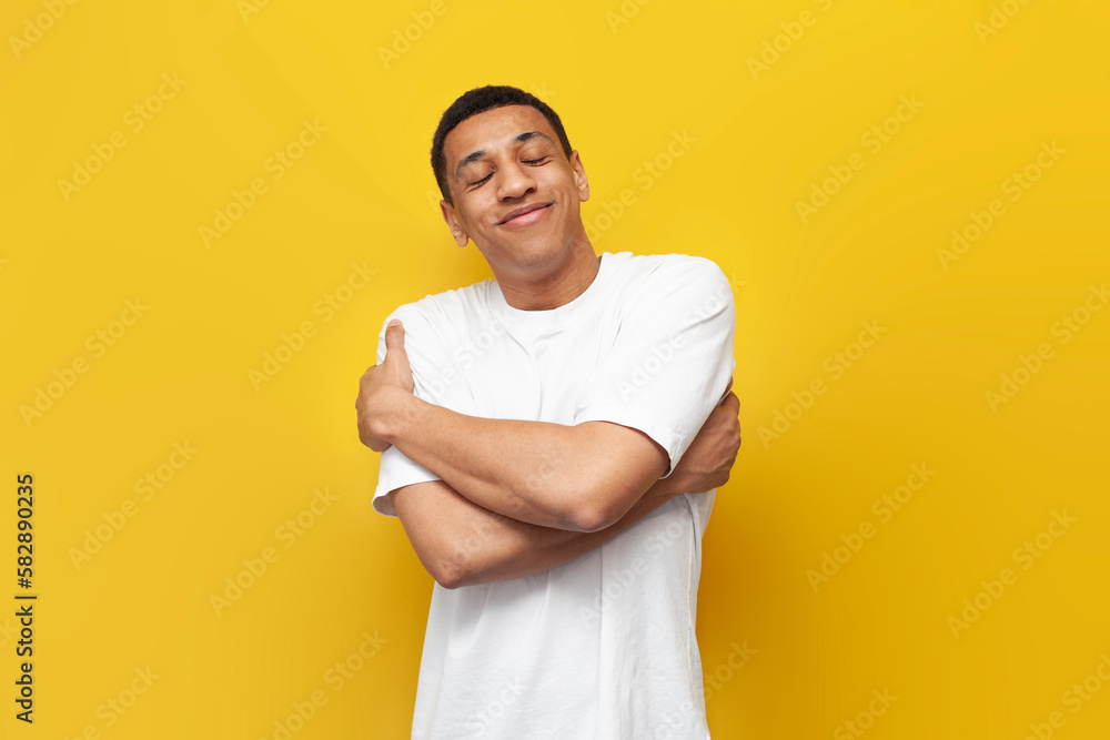 Ταπετσαρία young narcissistic african american guy in white t-shirt hugs himself on yellow
