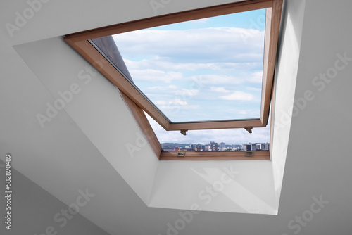 Fotografi Open skylight roof window on slanted ceiling in attic room