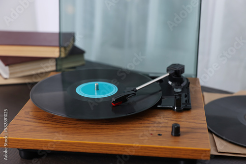 Retro turntable with vinyl record on wooden table