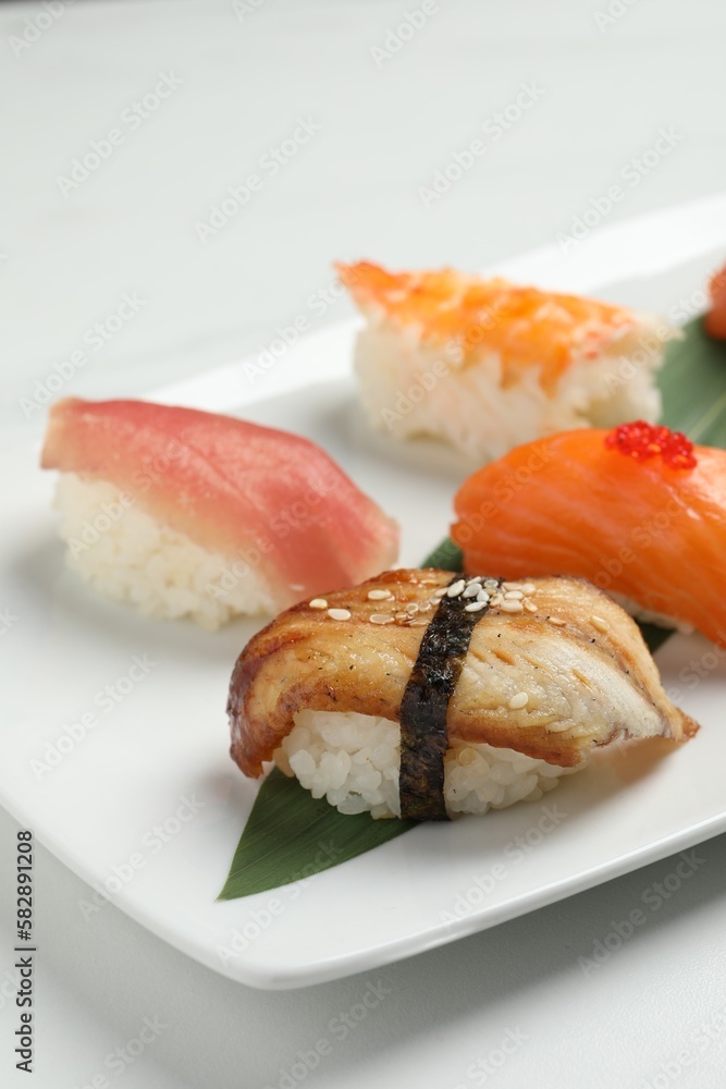 Plate with delicious nigiri sushi on white table, closeup Plate with delicious nigiri sushi on white table, closeup