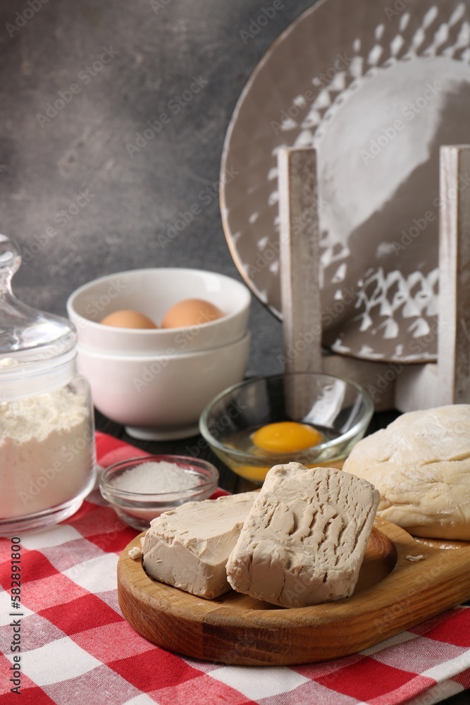 Compressed yeast, salt, flour, eggs and dough on wooden table Compressed yeast, salt, flour, eggs and dough on wooden table