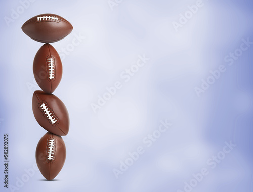 Stack of American football balls on blue background. Space for text