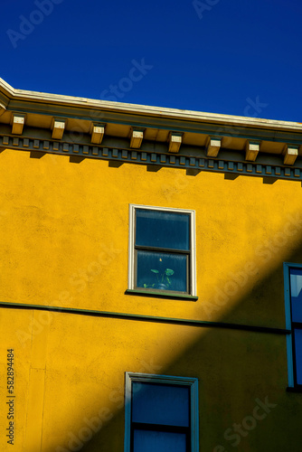 Sunstreak suburban city building with orange stucco cement exterior and decorative accent facade with windows and blue sky photo